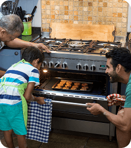 A family of three generation putting cookies in the oven together